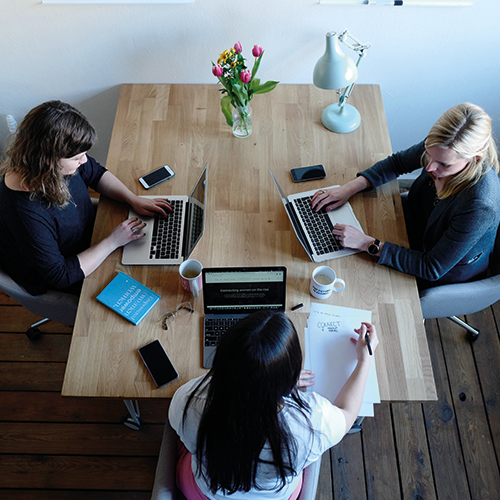 women sitting at desk with laptops