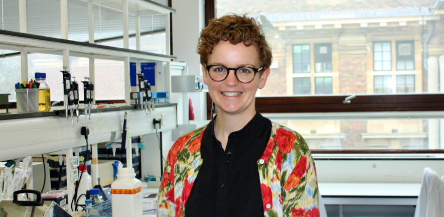 Camilla Godlee Camilla Godlee, smiling, standing in the laboratory wearing a floral cardigan, glasses, and with short hair